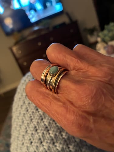 Close-up of a customer's hand wearing the two-tone spinner ring with a light blue Larimar stone.