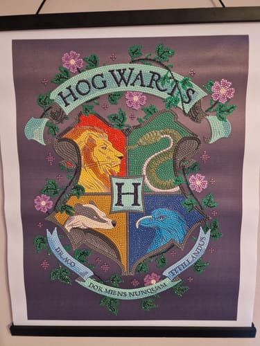 A reviewer's completed Hogwarts Crest Crystal Art Scroll, featuring the sparkling house crest and hanging on a wall.