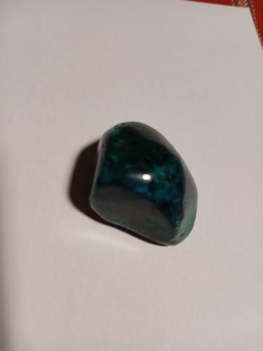 Photo d'un client montrant sa pierre de Dioptase polie, d'un vert foncé et brillant.
