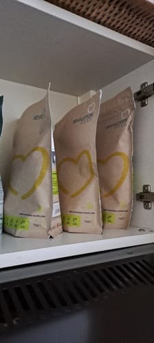 Customer's three bags of Superblend Protein Powder stocked in a white supplement cupboard.