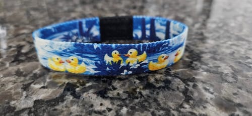 Customer's blue Ripple Effect Bracelet with a yellow rubber duck pattern, shown on a dark countertop.