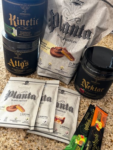 Customer's black jar of Nektar® superfood shown with a collection of other Ambrosia brand supplements on a counter.