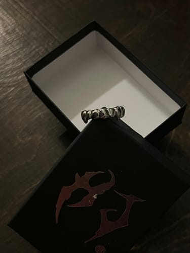 Customer's silver GRILL RING, designed to look like teeth, resting on its open black box.