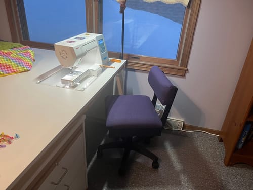 Customer's purple Arrow Hydraulic Sewing Chair pulled up to a sewing desk with a sewing machine.