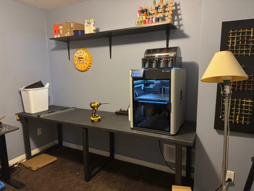 Customer's Bambu Lab H2S Combo printer set up on a long desk in a workshop.