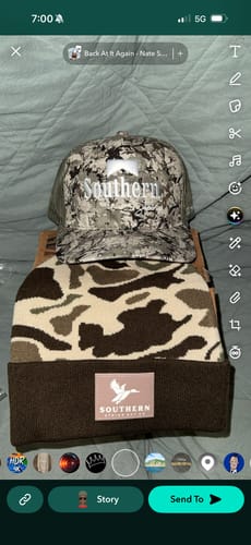 Reviewer's two hats from the Hat of the Month Crew: a camo trucker cap and a matching camo beanie.