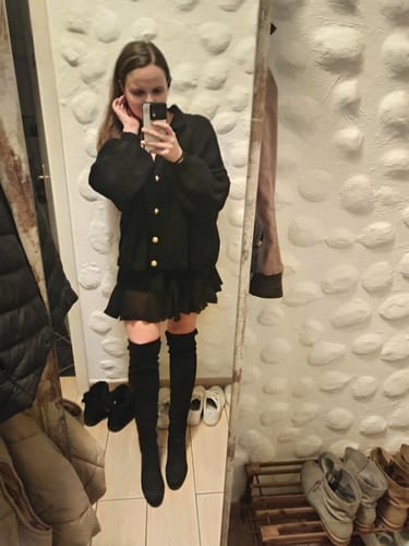 Kundin in einem Spiegel-Selfie, die das Bundle aus dem schwarzen Oversized-Cardigan „CozyGlam“ und dem Rock „Summer“ trägt.