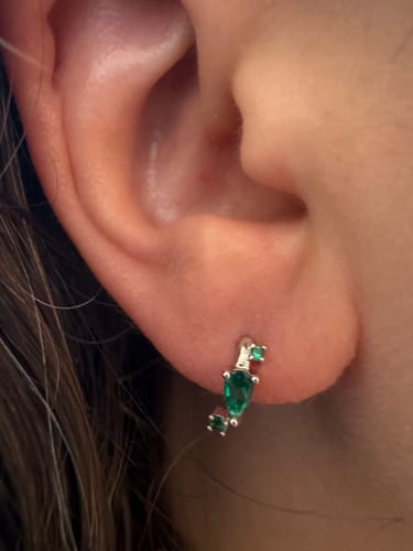 Close-up of a reviewer wearing the Ethereal huggies earring, showing its green stones.