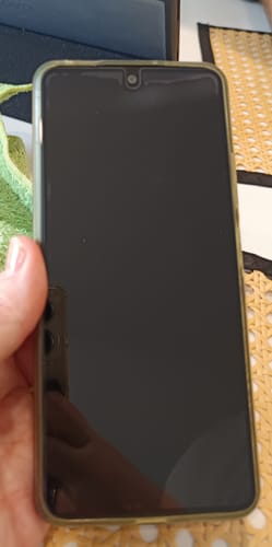 Ein Rezensent hält ein Handy, auf dem die Schutzfolie mit einer großen, sichtbaren Blase unten angebracht ist.