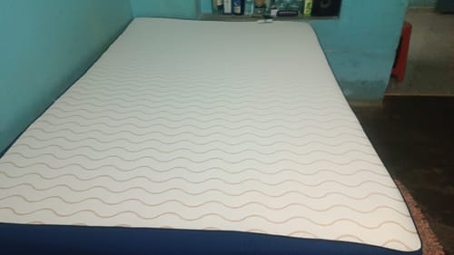 Customer's Flo Mattress Ortho with a white patterned top and blue base, fully expanded on a bed frame.