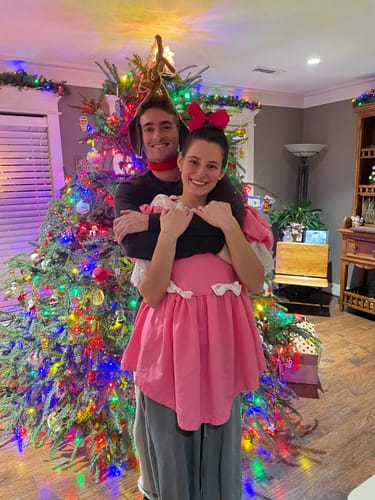 Reviewers dressed as the characters Maxy and Cindy Lou Woo for the Christmas Murder Mystery game, posing by a tree.