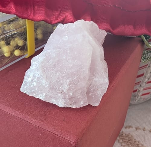Reviewer's raw, light pink crystal from their monthly subscription displayed on a red box.