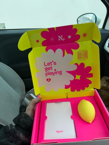 Reviewer holding the newly opened Lem Clitoral Massager in its colorful packaging.