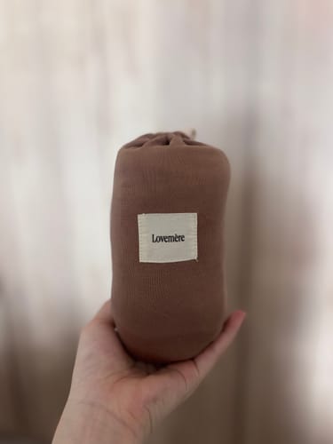 Customer holding the soft, brown travel pouch for the Lovemère Buttery Nursing Cover.