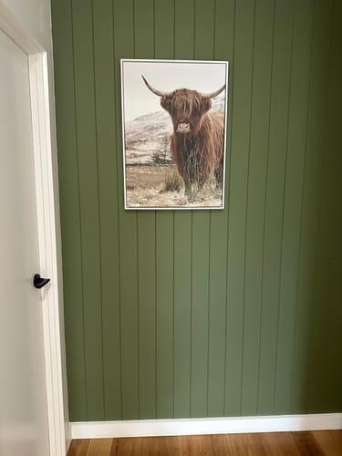 Customer's Highlander framed canvas hanging on a green paneled wall in an entryway.