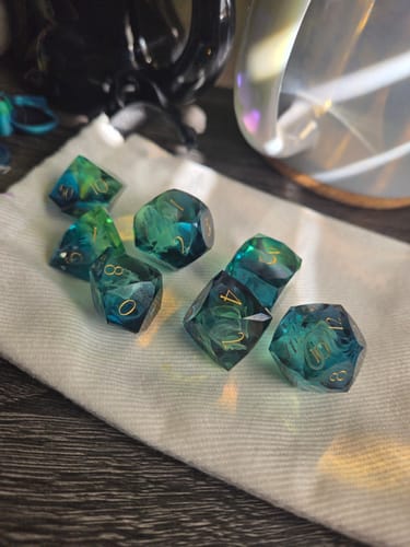 Customer's beautiful Tidebound Fate dice set with blue and green smoky details, displayed on a white cloth.