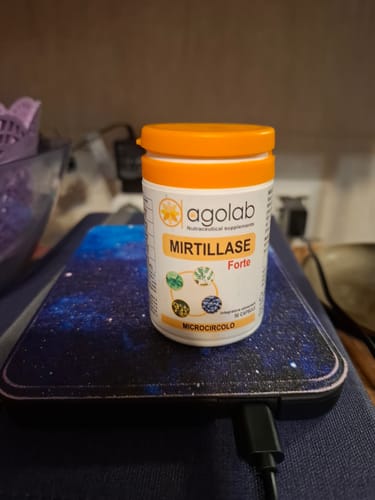 Un cliente mostra il barattolo bianco di Mirtillase Forte con tappo arancione, appoggiato su una scrivania.