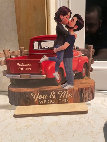 A customer's personalized wooden plaque showing a couple kissing by a red truck with 'You & Me We Got This' on the base.