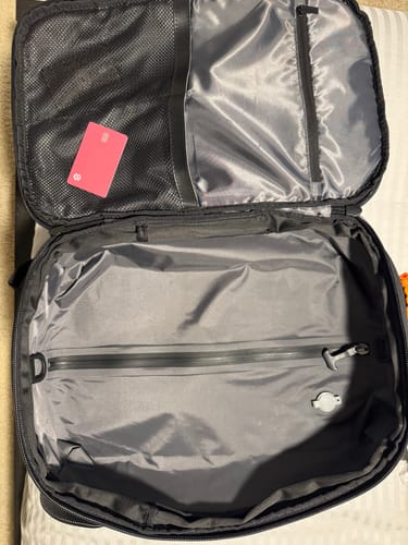 Customer's open travel bag with a pink SPOTMINDER tracker in a mesh pocket and a white one in the main compartment.