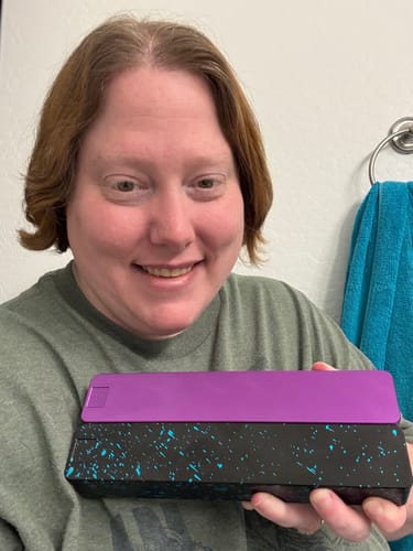 Customer smiling while holding their purple and black splatter-painted Weekly AM-PM Vitamin Case 2.0.