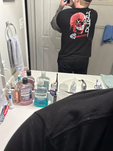 Reviewer's mirror selfie showing the back of their black Drippy Tee with a red skull graphic.