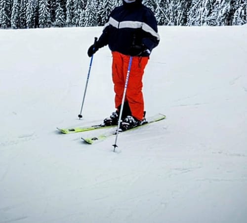 Reviewer skiing on a snowy slope wearing the Black Retro Track Chevron Stripe Snow Jacket.
