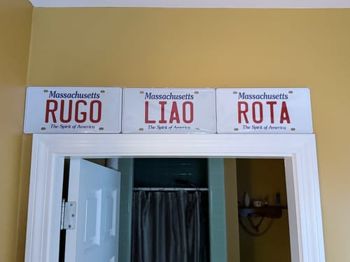 Customer's three customized Massachusetts Metal License Plates arranged side-by-side above a doorway in their home.