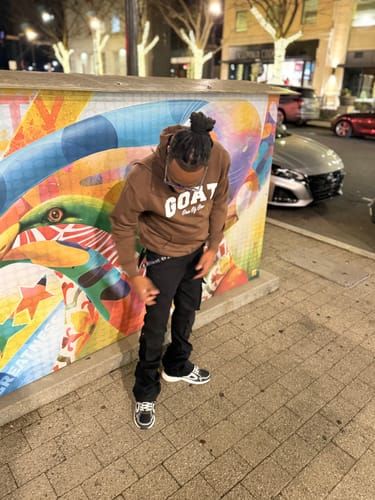 Customer wearing the black Vortex Cargo Stacked Denim pants, standing outdoors on a sidewalk at night.