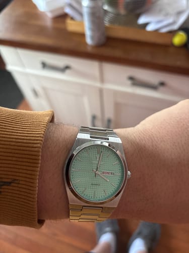 Customer wearing the Lucky Fours® Jaxon watch with a light green face and silver band on their wrist.