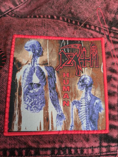 Reviewer's detailed Death Human square patch sewn onto a red denim jacket.