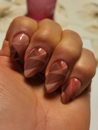Hand einer Kundin mit 'Pink Mirrors' UV-Gel-Nagelfolien in einem glänzenden, geometrischen Splitter-Design.
