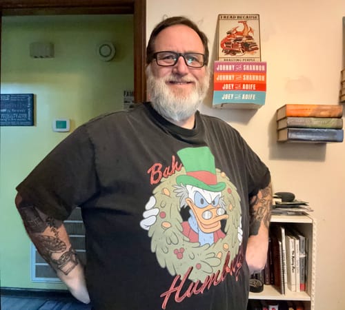 Reviewer smiling while wearing the black vintage 'Bah Humbug!' crewneck tee with a large Scrooge McDuck graphic.