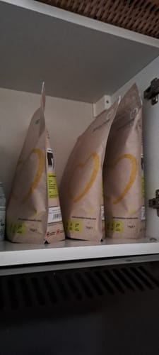Reviewer's three bags of Superblend Protein Powder organized on a shelf in a white cupboard.