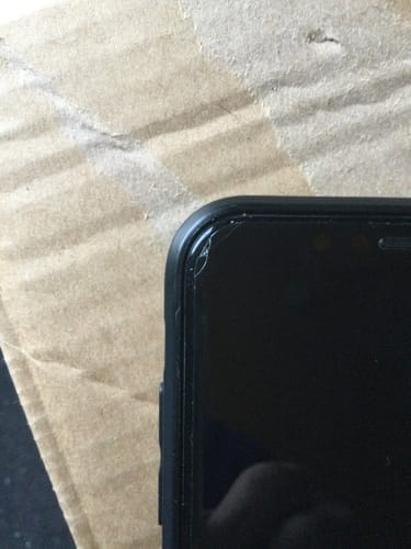 Nahaufnahme der gesprungenen 3-in-1-Schutzfolie des Kunden in der Ecke eines iPhones.