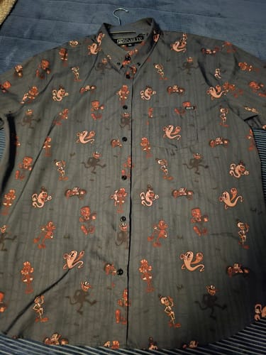 Reviewer's Spooky Soiree shirt laid flat, showing the detailed cartoon monster pattern on the dark gray fabric.