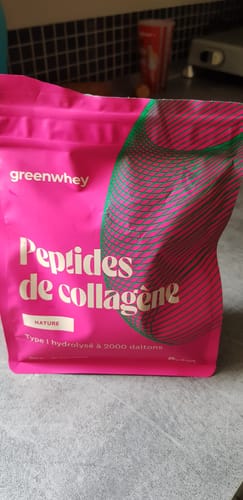 Client montrant le sachet rose vif des Peptides de Collagène, saveur Nature, sur un comptoir.