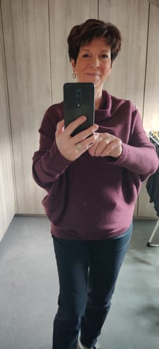 Customer taking a mirror selfie showing a closer view of the Amethyst Plum Asymmetric Draped sweater's neckline.