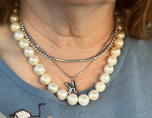 Reviewer wearing the silver Bubble Letter 'K' Initial Necklace, layered with a pearl and a chain necklace.