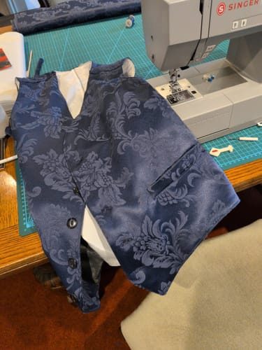 Reviewer's Singer Heavy Duty HD6705 machine on a work table with a blue patterned vest project in progress.
