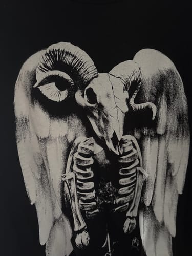 Close-up of a reviewer's black Aries Zodiac Shirt, detailing the winged ram skeleton graphic.