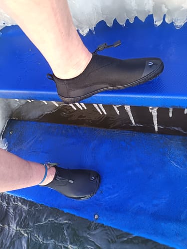 Asiakkaan mustat Vaistoa Vire -avantopaljasjalkakengät jalassa sinisellä matolla avannon reunalla.