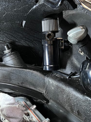 Reviewer's black Motion Raceworks oil catch can installed in an engine bay, showing the top filter.