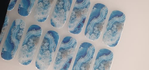 Ein Kunde zeigt die unbenutzten „Glacier Marble“ UV-Gel-Nagelfolien auf dem Trägerblatt.