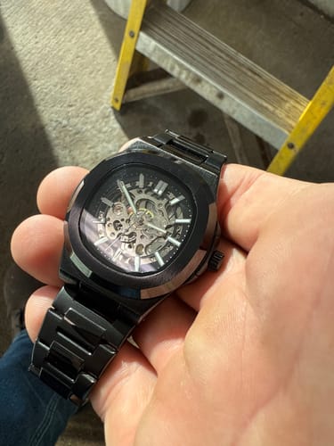 A customer holds their black Lucky Fours® Skeleton watch, showing its intricate face.