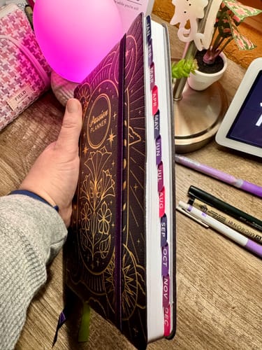 Reviewer holding a closed planner, showing the colorful Monthly Tabs attached along the edge of the pages.