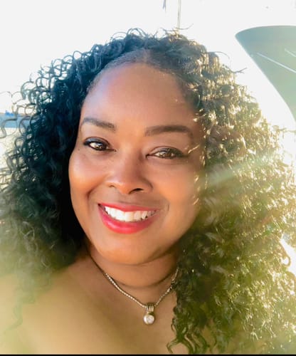 Reviewer smiling while wearing the full, curly Outre Quick Weave Half Wig.