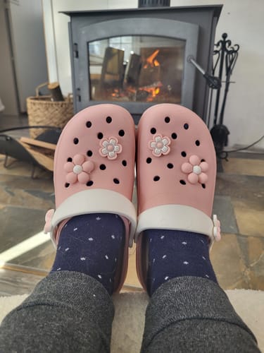 Reviewer wearing pink Blossom Platform Sandals with patterned socks while relaxing in front of a fireplace.