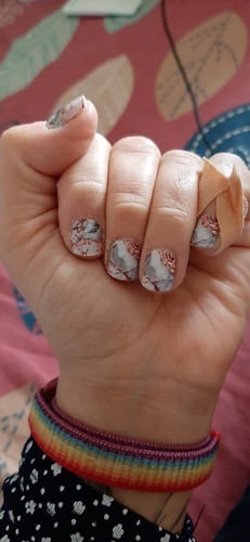 Nahaufnahme der Hand einer Kundin, die die schönen Marble Rose Nagelfolien trägt.