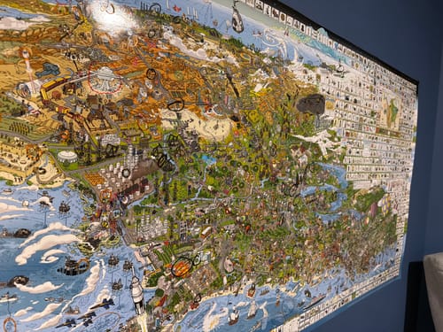 Customer's large, detailed World's Greatest Search & Discover poster mounted on a dark blue wall.