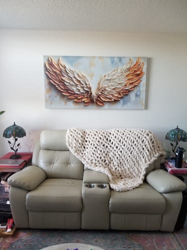 Reviewer's Ember Ascend angel wings canvas hung centered above a beige sofa in their apartment.